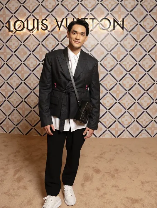 Afgan tampil mengenakan blazer hitam dengan belt tali, serasi dengan celananya. Dipadukan inner kemeja putih yang cocok dengan sneakersnya. Serta membawa shoulder bag box Louis Vuitton. [Instagram/@afgan__]