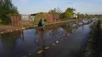 Gadis muda menggendong seorang anak di punggungnya melalui jalan yang tergenang banjir di dekat waduk yang meluap di Hamanskraal, Pretoria, Afrika Selatan, Jumat, 26 Mei 2023. (AP Photo/Themba Hadebe)