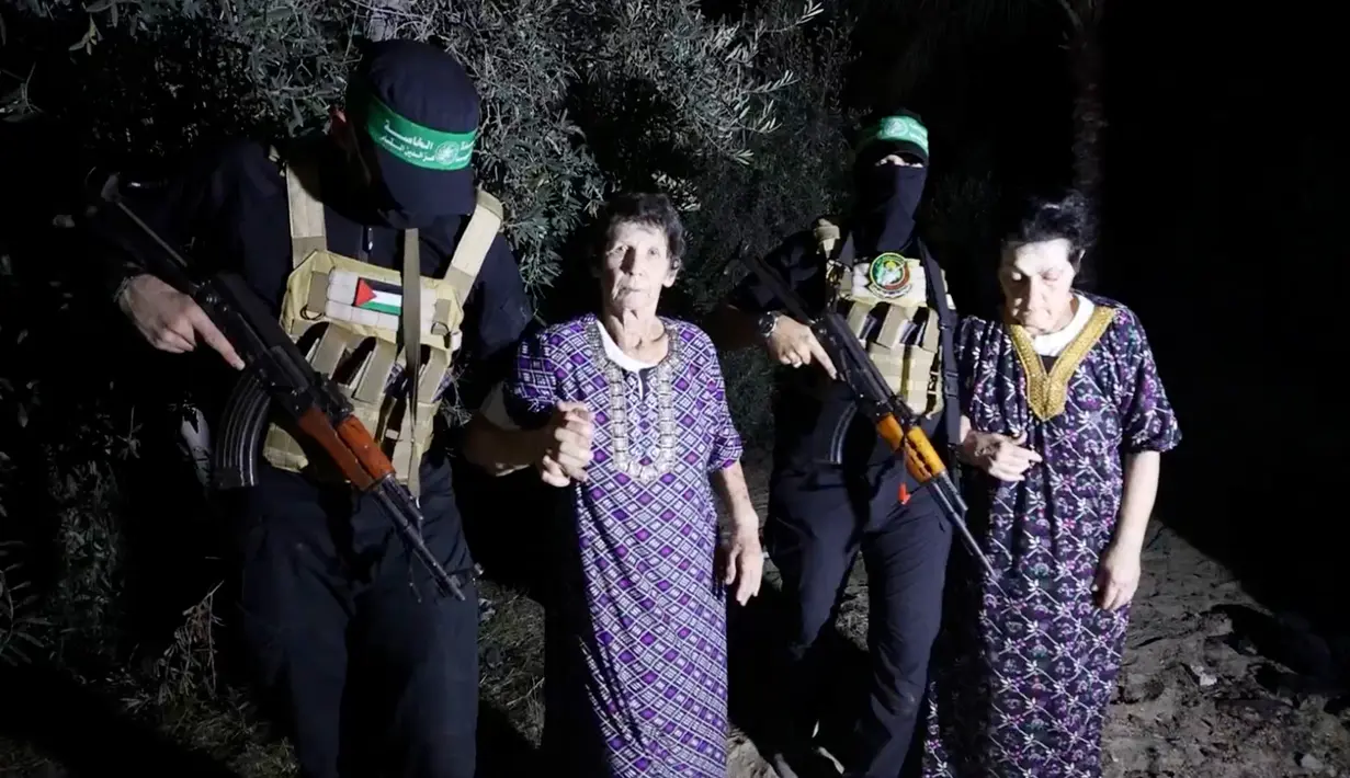 Yocheved Lifshitz (85, tengah) dan Nurit Cooper (79) dikawal oleh Hamas saat mereka dilepaskan ke Palang Merah di lokasi yang tidak diketahui, Senin (23/10/2023). (Al Qassam brigades via AP)