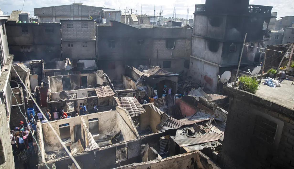Warga berdiri di tengah rumah mereka yang rusak usai ledakan truk pengangkut BBM di Cap-Haitien, Haiti, 14 Desember 2021. Banyaknya korban jiwa terjadi karena orang-orang mengerumuni kendaraan untuk mengumpulkan bahan bakar yang tumpah. (AP Photo/Joseph Odelyn)