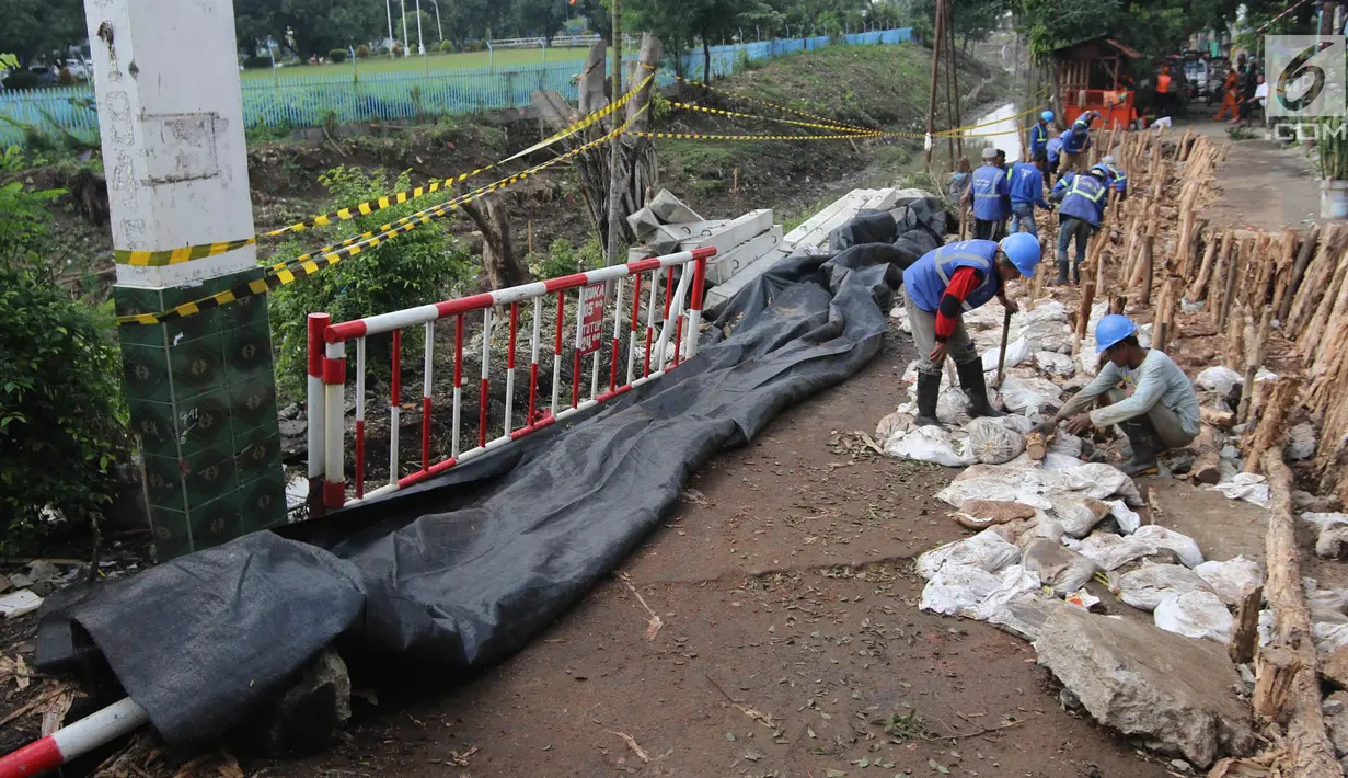 Petugas Sudin Sumber Daya Air Jakarta Timur melakukan perbaikan jalan ambles di Jalan Al-Mujahidin, Cipinang, Pulogadung, Jakarta Timur, Rabu (21/2). Jalan tersebut ambles sepanjang 30 meter dan kedalaman 1,5 meter. (Liputan6.com/Arya Manggala)
