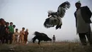 Seorang pria dan anak-anak menonton pertandingan sabung ayam di pinggiran Islamabad, Pakistan, 15 Desember 2021. Pakistan terkenal memiliki jenis ayam petarung paling tua di dunia dengan kekuatan fisik dan mental bertarungnya. (AP Photo/Rahmat Gul)