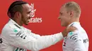 Juara F1 GP Jerman, pembalap Mercedes Lewis Hamilton bersama pembalap Ferrari dari Finlandia, Vatteri Bottas yang menempati posisi kedua merayakan kemenangan di ats podium Sirkuit Hockenheim, Minggu (22/7). (AP/Jens Meyer)