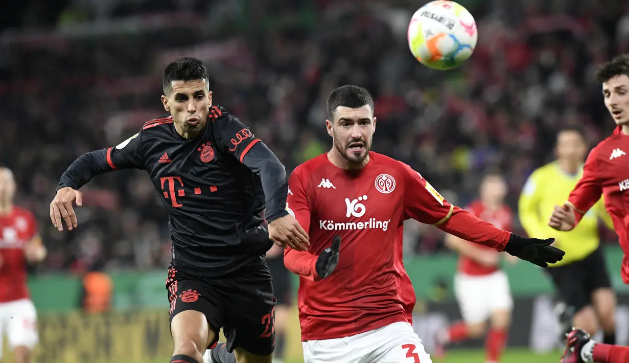 Bek Bayern Muenchen, Joao Cancelo berebut bola dengan bek Mainz 05, Aaron Martin selama pertandingan babak 16 besar Piala Jerman (DFB Pokal) di Mewa Arena, Mainz, Jerman (1/2/2023). Bermain sebagai starter, Cancelo mencetak satu assist dalam laga debutnya bersama Bayern. (AFP/Thomas Kienzle)
