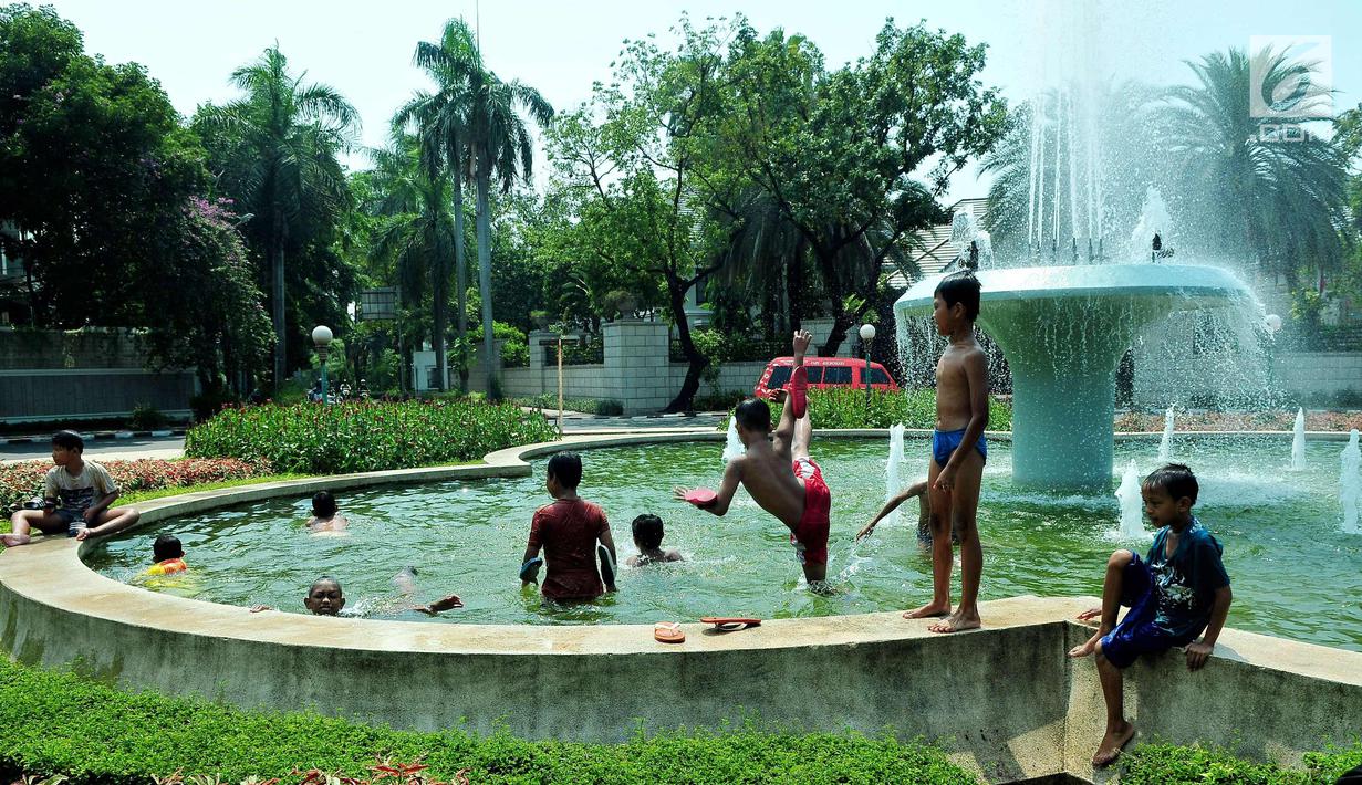 Sejumlah anak mandi bermain di bundaran air mancur Jalan Teuku Umar, Jakarta Pusat, Sabtu (23/9). Cuaca panas ibu kota memaksa anak-anak menceburkan diri di kolam untuk menyejukkan badan. (Liputan6.com/Helmi Afandi)
