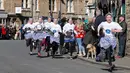 Amy Butler berlari memimpin lomba lari dengan membawa pancake dalam lomba tahunan Pancake Trans-Atlantic di kota Olney, Buckinghamshire, Inggris, Selasa (5/3). Peserta juga harus membolak-balikan pancake sambil tetap berlari. (AP/Frank Augstein)