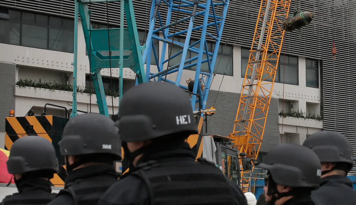 Penjinak bom dari kepolisian Hong Kong melihat proses pengangkatan bom era Perang Dunia II yang ditemukan di lokasi konstruksi di distrik Wan Chai, Kamis (1/2). Para ahli berhasil menjinakkan bom yang kondisinya sudah sedikit hancur itu. (AP/Vincent Yu)