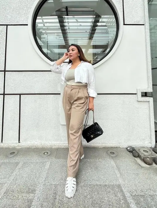 Angelica juga tampil dengan kemeja crop top putih sebagai luaran dengan inner abu-abu dipadukan celana coklat sambil membawa tas Chanel hitam. [@angelicamanopo]