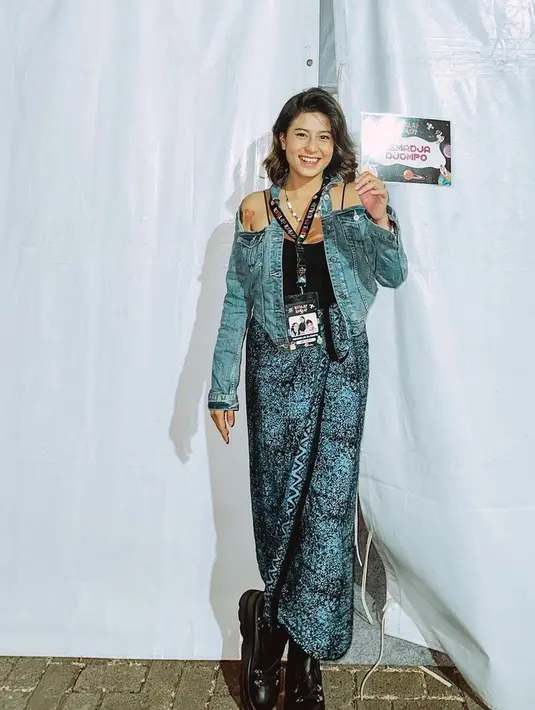 Mengenakan atasan jaket denim cut out dan spaghetti strap hitam, Karina memadukannya dengan kain batik warna biru dan sepatu bootsnya.  [@narinkovilda]