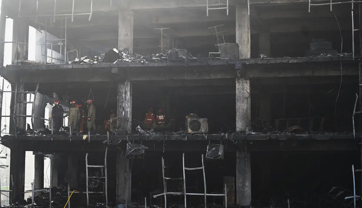 <p>Anggota Pasukan Tanggap Bencana Nasional dan petugas pemadam kebakaran memeriksa sebuah gedung komersial sehari setelah kebakaran terjadi di New Delhi, India, Sabtu (14/5/2022). Kebakaran yang melanda gedung perkantoran empat lantai di Delhi, pada Jumat 13 Mei 2022, menewaskan sedikitnya 27 orang dan melukai sedikitnya 12 orang, kata layanan darurat. (Sajjad HUSSAIN / AFP)</p>