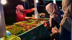Penjual melayani pembeli selama bulan suci Ramadhan di pasar malam di provinsi Narathiwat, Thailand selatan (21/4/2022). Penjual makanan jalanan mendirikan kios mereka untuk menjual makanan kepada umat Muslim untuk berbuka puasa. (AFP/Madaree Tohlala)