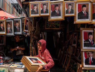 Seorang pembeli membawa foto presiden terpilih Indonesia Prabowo Subianto dan wakil presiden terpilih Gibran Rakabuming Raka menjelang pelantikan mereka pada 20 Oktober, di sebuah toko di Jakarta pada 19 Oktober 2024. (JUNI KRISWANTO/AFP)