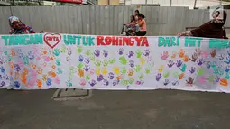 Warga membentangkan spanduk bekas Cap tangan anak-anak Indonesia, di Kawasan Car Free Day, Jakarta (24/9). Spanduk sepanjang satu kilometer tersebut untuk menunjukkan dukungan kepada Etnis minoritas Rohingya di Myanmar. (Liputan6.com/Johan Tallo)