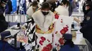 Seorang perempuan Jepang berkimono yang merayakan ulang tahun ke-20, melewati pemeriksaan keamanan untuk berpartisipasi dalam upacara resmi, yang biasa disebut upacara Kedewasaan di Yokohama dekat Tokyo, Senin (9/1/2023). Jepang menurunkan usia dewasa dari 20 tahun menjadi 18 tahun pada 2022. (AP Photo/Eugene Hoshiko)