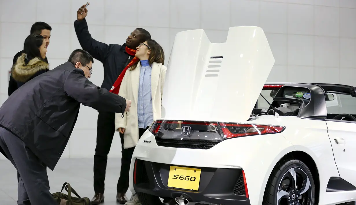 Pengunjung berselfie disamping mobil Honda S660 di markas besar Honda Motor Co di Tokyo, Jepang, (24/2). Mobil Honda S660 adalah mobil sport yang memiliki dua tempat duduk berkatagori mobil yang sangat kecil. (REUTERS/Thomas Peter)