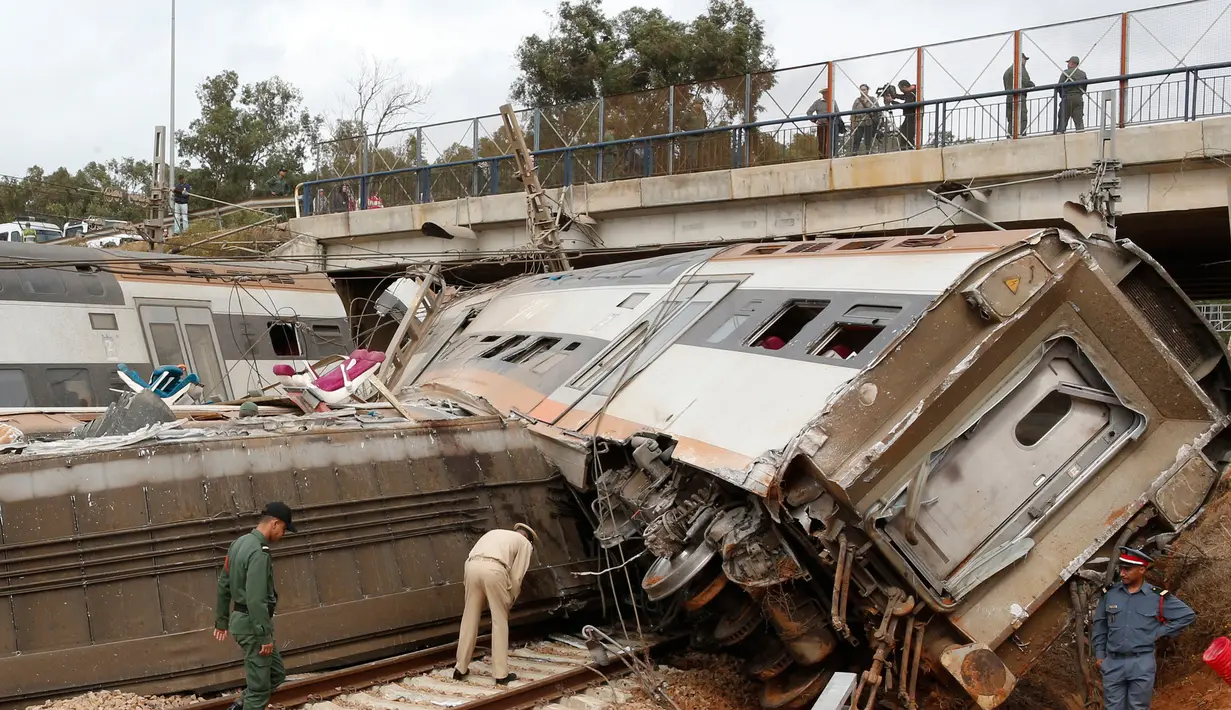 Aparat kepolisian berdiri dekat sebuah kereta api yang terguling di Sidi Bouknadel, Maroko, Selasa (16/10). Kereta yang dalam perjalanan dari Rabat menuju Kenitra telah keluar jalur di sekitar 20 km dekat Sidi Bouknadel. (AP/Abdeljalil Bounhar)