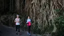 Dua perempuan berolahraga melewati akar pohon beringin di sepanjang jalur pendakian di Hong Kong, 22 Februari 2020. Warga Hong Kong memilih pergi ke area perbukitan untuk mencari udara segar dibandingkan harus tinggal di pusat kota dan dibayangi ketakutan akan wabah virus corona. (VIVEK PRAKASH/AFP)