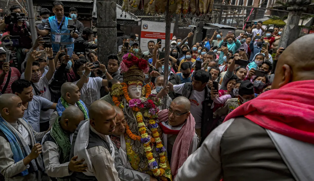 Para pendeta membawa Seto Machindranath, dewa pelindung Nepal, selama festival kereta di Kathmandu (9/4/2022). Dalam ritual ini, setiap tahun mereka memandikan dan mengecat ulang patung Dewa Seto Machindranath. (AFP/Prakash Mathema)