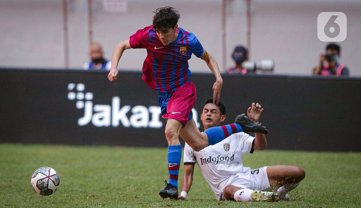 Pemain Barcelona U-18 Joan Anaya Balaña (kiri) menggiring bola meninggalkan pemain Bali United U-18 Anak Agung Dwi Trisna Putra pada pertandingan International Youth Championship (IYC) 2021 di Jakarta International Stadium (JIS), Jakarta, Minggu (17/4/2022). (Liputan6.com/Faizal Fanani)