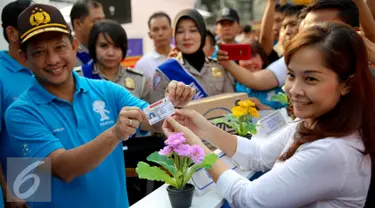 Kapolda Metro Jaya, Irjen Pol Tito Karnavian (kiri) memberikan SIM A yang telah selesai secara online kepada warga dalam rangka HUT Polantas yang ke-60 di Bundaran HI, Jakarta, Minggu (27/9/2015). (Liputan6.com/Faizal Fanani)