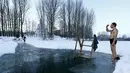 Seorang pria bersiap untuk mandi di dalam air es di danau dalam prosesi perayaan Epifani Ortodoks di Minsk, Belarusia (19/1/2016). Umat Kristen Ortodoks merayakan Epifani yang jatuh pada 19 Januari. (REUTERS/Vasily Fedosenko)