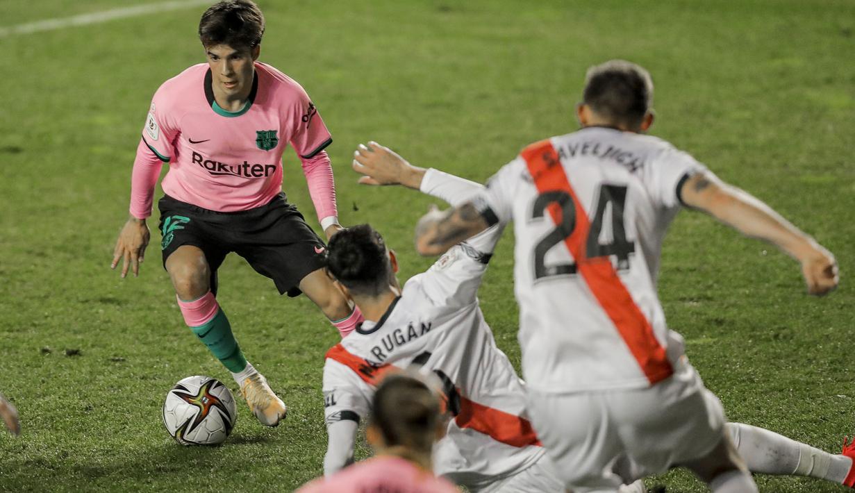 Pemain Barcelona, Riqui Puig (kiri) mengecoh pemain Rayo Vallecano pada laga babak 16 Besar Copa del Rey di Vallecas stadium, Madrid, Kamis (28/1/2021). (Foto: AP/Manu Fernandez)