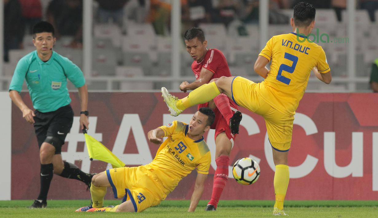 Kapten Persija Jakarta, Ismed Sofyan (tengah) melepaskan tembakan melewati adangan dua pemain Song Lam Nghe An FC pada laga Piala AFC 2018 di Stadion Utama GBK, Senayan, Jakarta, (13/3/2018). Persija Jakarta menang 1-0. (Bola.com/Nick Hanoatubun)