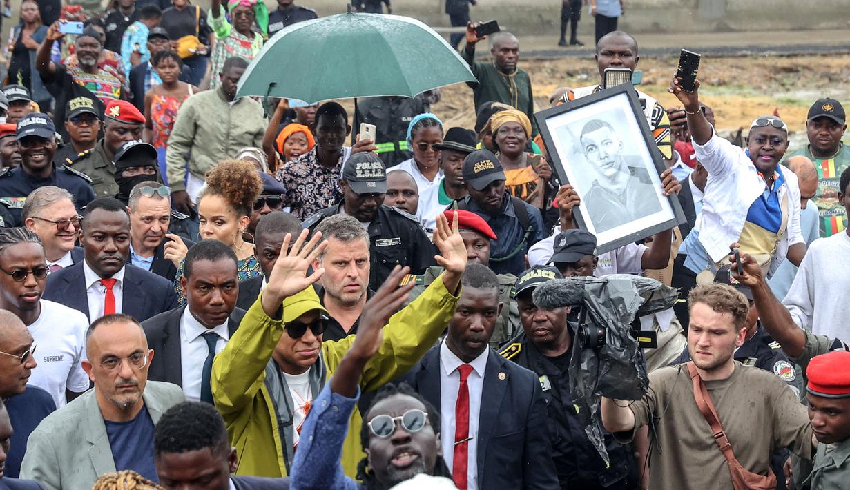 Pemain Paris Saint-Germain dan kapten Timans Prancis, Kylian Mbappe (tengah) tiba untuk mengunjungi sekolah umum dwibahasa Bonendale, yang direnovasi oleh yayasan Inspired By Kylian Mbappe Foundation (IBKM), di Douala pada 8 Juli 2023. (AFP/Daniel Beloumou Olomo)