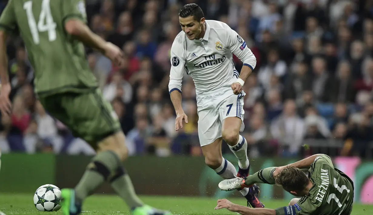 Cristiano Ronaldo berusaha melewati hadangan pemain Legia Warszawa, Jakub Rzezniczak pada laga grup F Liga Champions di Santiago Bernabeu stadium, Madrid, Rabu (19/10/2016) dini hari WIB. (AFP/Javier Sorano)  