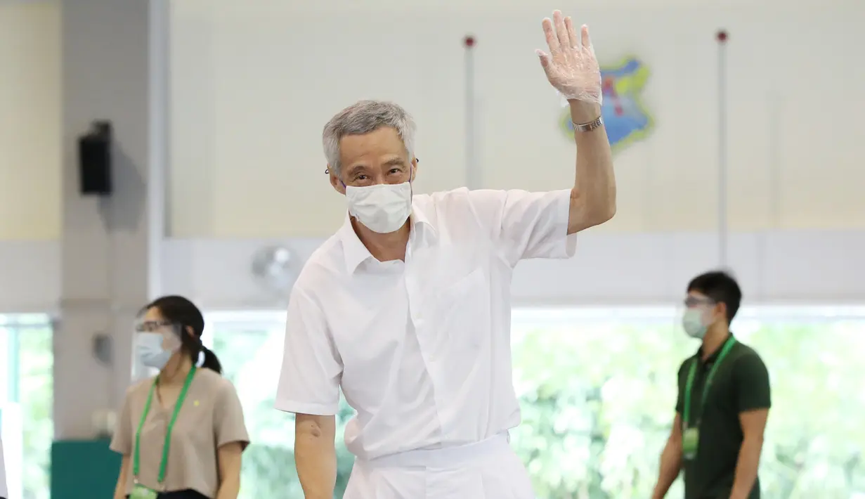 PM Lee Hsien Loong melambai saat memberikan suara dalam pemilu di TPS Sekolah Dasar Alexandra, Singapura, Jumat (10/7/2020). Pemilu di tengah pandemi COVID-19, warga Singapura memberikan suara dengan mengenakan masker dan sarung tangan plastik. (Ministry of Communications and Information via AP)