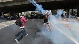 Petugas menghalau gas air mata yang dilemparkan para pengunjuk rasa di Caracas, Venezuela, (4/4). Para demonstran berusaha untuk menemani anggota parlemen oposisi dalam sesi wacana penghapusan Mahkamah Agung. (AP Photo / Fernando Llano)