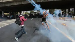 Petugas menghalau gas air mata yang dilemparkan para pengunjuk rasa di Caracas, Venezuela, (4/4). Para demonstran berusaha untuk menemani anggota parlemen oposisi dalam sesi wacana penghapusan Mahkamah Agung. (AP Photo / Fernando Llano)