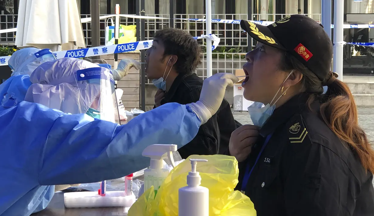 Seorang pekerja medis mengumpulkan sampel sampel swab dari penduduk di daerah penguncian di distrik Jingan di Shanghai barat (4/4/2022). Pengiriman petugas kesehetan untuk membasmi wabah COVID-19 yang menyebar dengan cepat di kota terbesar di China. (AP Photo/Chen Si)