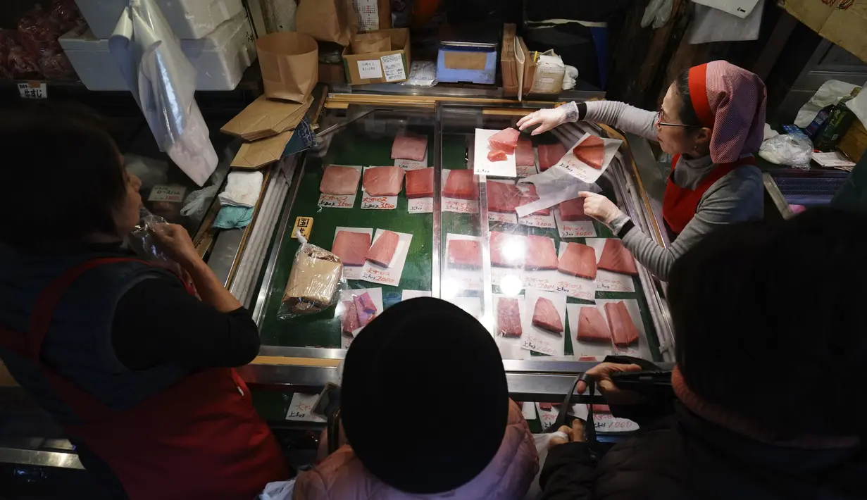 Pedagang melayani pembeli yang sedang mencari bahan-bahan untuk membuat makanan tahun baru atau osechi di Pasar Tsukiji, Tokyo, Jepang, Kamis (26/12/2019). Osechi akan ditata rapi dalam kotak kayu bersusun yang disebut jubako. (AP Photo/Eugene Hoshiko)