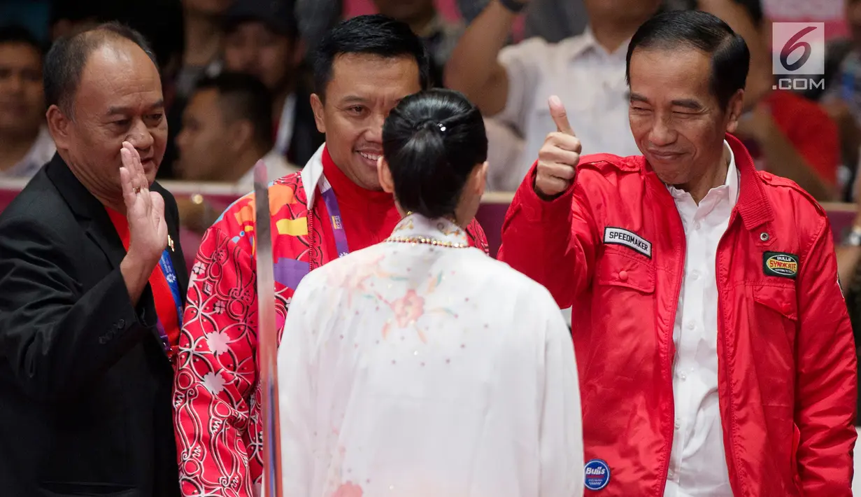 Presiden Joko Widodo mengacungkan jempol memberi semangat atlet wushu Indonesia, Lindswell Kwok saat bertanding di Asian Games 2018, Jakarta, Senin (20/8). Lindswell menyumbang emas kedua untuk Indonesia. (Bola.com/Vitalis Yogi Trisna)