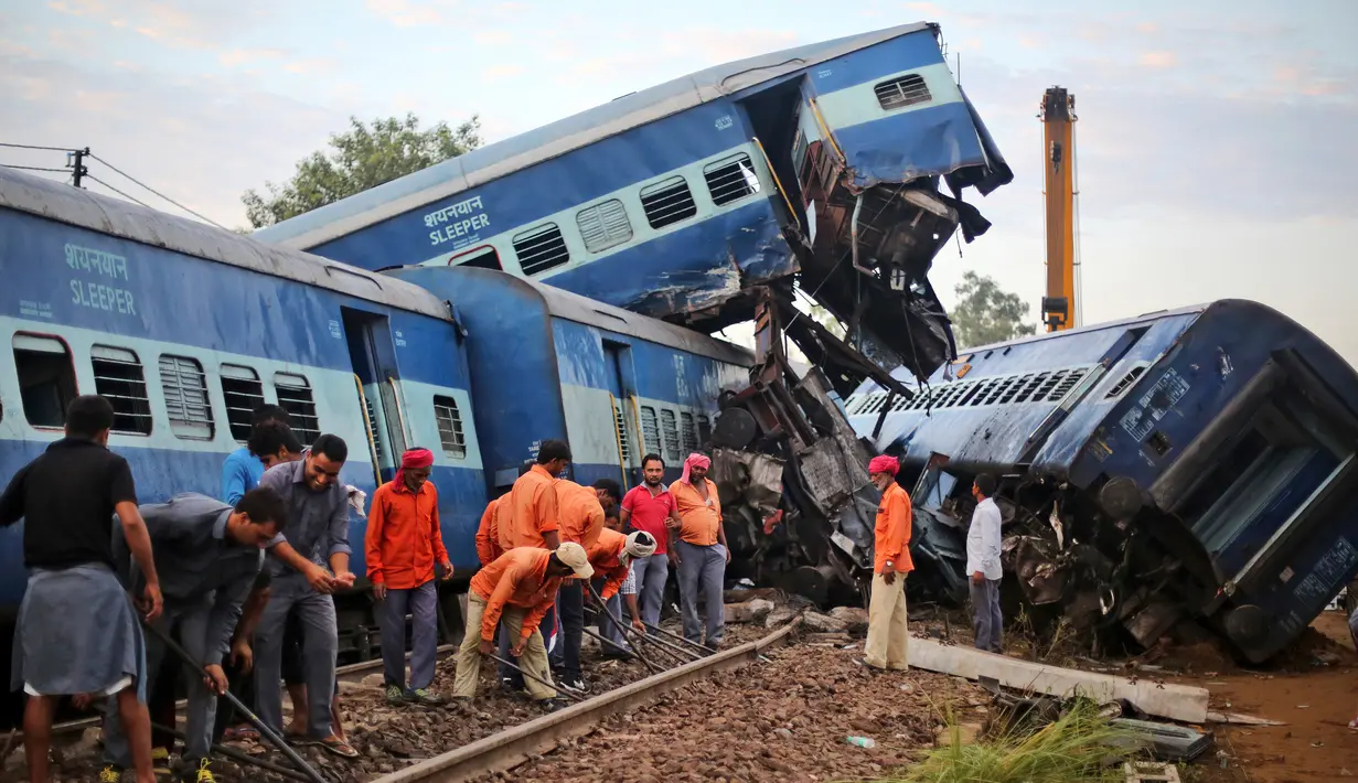 Pekerja memperbaiki rel dekat sebuah kereta api yang tergelincir hingga keluar jalur di Negara Bagian Uttar Pradesh, India, Minggu (20/8). Kecelakaan ini merupakan insiden yang melibatkan kereta penumpang keempat pada tahun ini. (AP/Altaf Qadri)