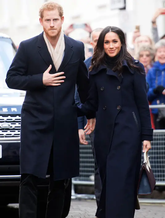 Pangeran Harry dan tunangannya, Meghan Markle setibanya pada acara amal untuk memperingati Hari AIDS Sedunia di Nottingham, Jumat (1/12). Pangeran Harry dan Meghan Markle sama-sama mengenakan outerwear warna biru navy. (Jeremy Selwyn/Pool Photo via AP)