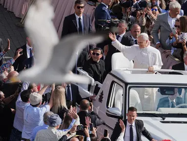 Seekor burung terbang melintas saat Paus Leo XIV menggunakan popemobile berkeliling Lapangan Santo Petrus Basilika di Vatikan, Minggu 18 Mei 2025. (Jacquelyn Martin/POOL/AFP)