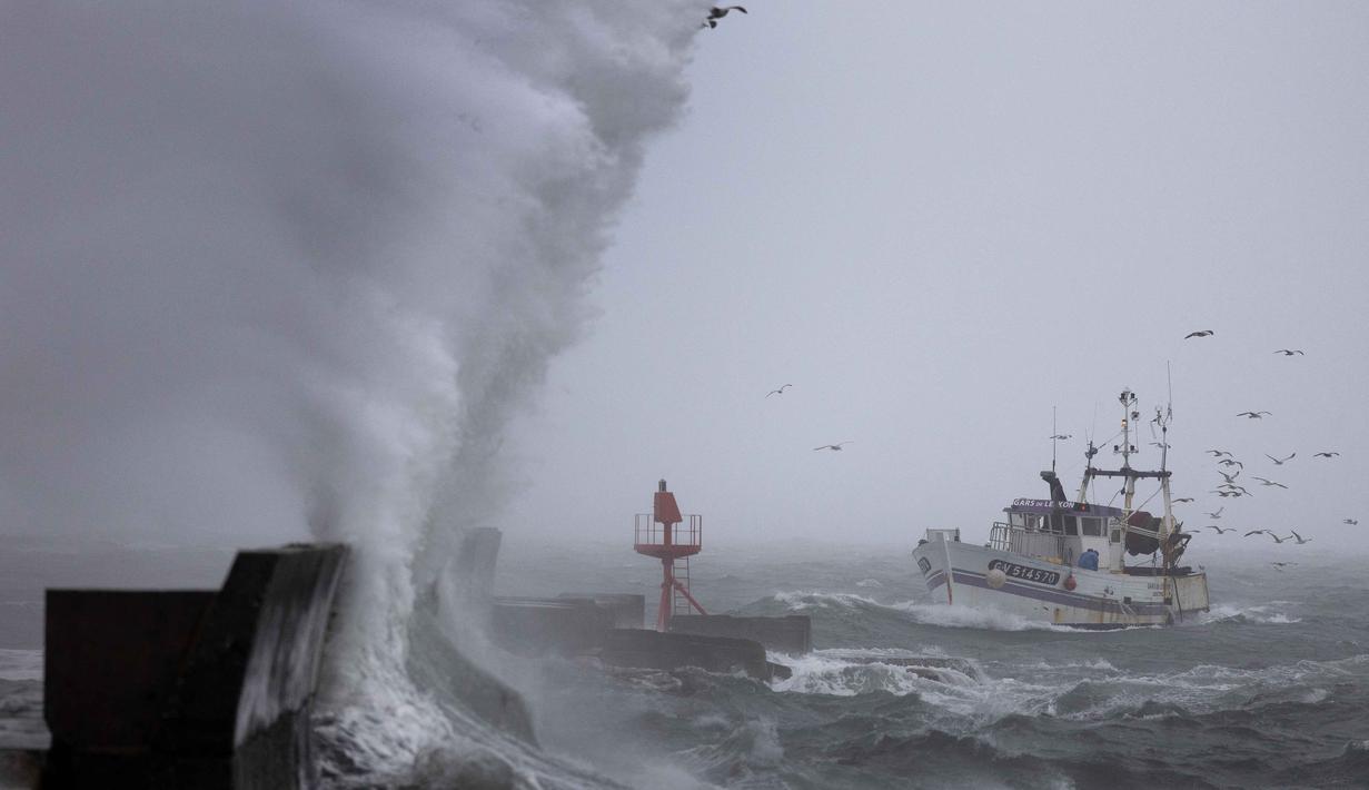 Sebuah perahu nelayan tiba di pelabuhan Plobannalec-Lesconil, Prancis Barat, pada 22 Oktober 2025, saat gelombang besar dan angin kencang menerjang pantai selama badai Benjamin melintas. (Fred TANNEAU/AFP)