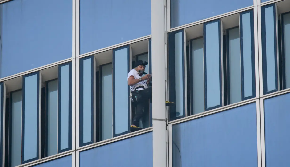 Urban climber atau pemanjat gedung, Alain Robert membuat skala saat memanjat Menara Lotte World di Seoul, Korea Selatan (6/6). Alain Robert gagal menaklukan gedung setinggi 123 lantai karena dicegat dan diamankan petugas setempat. (AFP/Ed Jones)