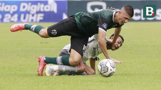 Pemain Persikabo 1973, Bruno Dybal, terjatuh saat berebut bola dengan pemain Persib Bandung, Beckham Putra, pada laga uji coba di Stadion Pakansari, Bogor, Minggu (27/11/2022). (Bola.com/M iqbal Ichsan)