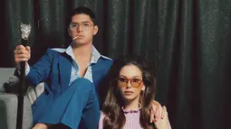 Posisi duduk mereka, dengan Al yang santai di kursi dan Alyssa yang berpose di lantai dengan tangan di pundak Al, menghadirkan suasana harmonis namun penuh pesona. Mereka menggunakan kacamata berwarna yang semakin memperkuat kesan vintage, memberi nuansa elegan ala era 70-an. Kombinasi ini berhasil menciptakan potret yang tak hanya meniru, tapi juga memberi nuansa baru dari gaya klasik Elvis dan Priscilla. (Liputan6.com/IG/@alyssadaguise)