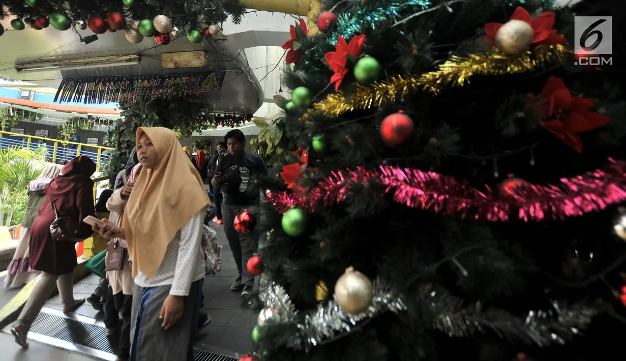 Pejalan kaki melintasi pohon Natal yang menghiasi tempat penyeberangan orang (TPO) Kota Tua, Jakarta, Kamis (20/12). TPO yang menghubungkan Stasiun Kota Tua dan Halte Transjakarta tersebut berhias ornamen Natal dan Tahun Baru. (Merdeka.com/Iqbal Nugroho)