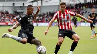 Striker Arsenal, Gabriel Jesus, dikawal oleh bek Brentford, Aaron Hickey, saat kedua tim berhadapan pada laga pekan kedelapan Premier League 2022/2023 di Gtech Community Stadium, London, Minggu (18/9/2022). (Ian Kington / AFP)