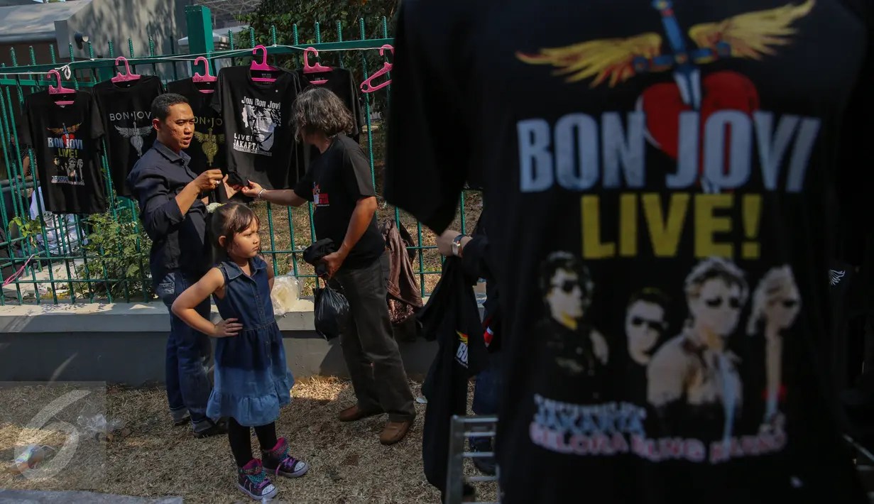 Seorang pengunjung membeli kaos Bon Jovi yang dijajakan pedagang di luar Stadion Gelora Bung Karno, Jakarta, Jumat (11/9/2015). Grup band asal Amerika itu akan menggelar konser ‘Bon Jovi Live! Jakarta' nanti malam di arena GBK.(Liputan6.com/Faizal Fanani)