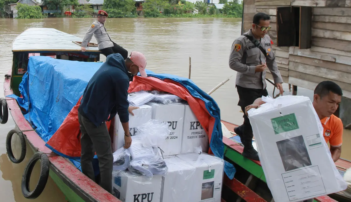 Petugas pemilu menurunkan kotak suara dari perahu saat distribusi perlengkapan pemilu ke desa-desa terpencil, di Pemulutan, Sumatra Selatan, Selasa, 13 Februari 2024. (AP Photo/Muhammad Hatta)