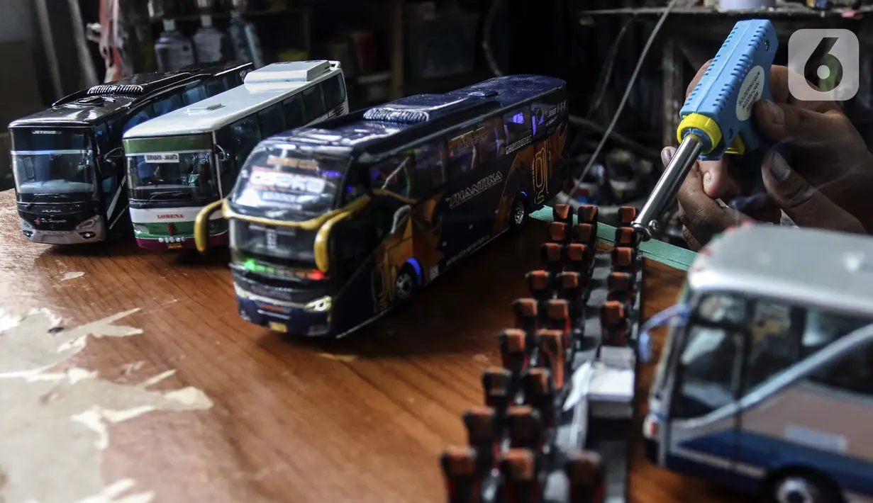 Perajin menyelesaikan pembuatan miniatur bus di Workshop Belang Bentong, Limo, Depok, Jawa Barat, Jumat (14/1/2022). Kerajinan miniatur bus berbahan baku akrilik dan resin tersebut dipasarkan ke berbagai daerah dengan harga Rp 700 ribu hingga Rp 1 juta per unit. (Liputan6.com/Johan Tallo)