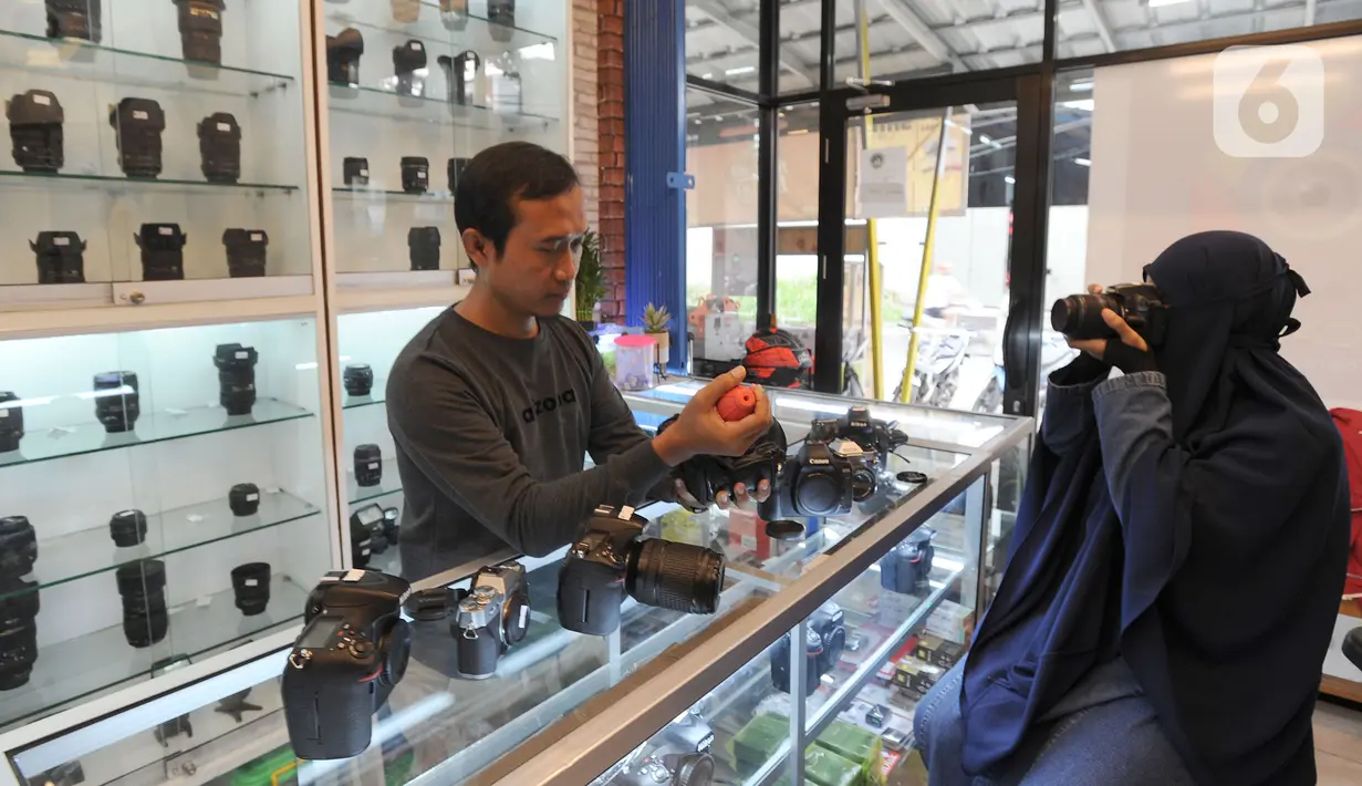 Calon pembeli mencoba kamera bekas  yang dijual belikan di CSZ Camera di kawasan Pondok jagung, Tangerang Selatan, Banten, Senin (20/12/2021). Dari yang semula perhari dijual 4 kamera saat ini mencapai 6 hingga 7 kamera dengan harga antara Rp 3 hinga Rp 21 juta. (merdeka.com/Arie Basuki)