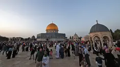 Umat ​​Muslim berfoto di depan masjid Kubah Batu setelah sholat Idul Fitri, yang menandai akhir bulan suci Ramadhan, di kompleks masjid Al-Aqsa di Yerusalem Lama pada 2 Mei 2022. (AFP/Ahmad Gharabli)