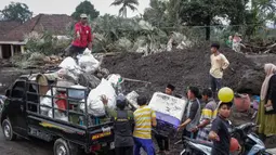 Kerusakan rumah dan fasilitas umum ini tidak hanya diakibatkan oleh awan panas guguran, melainkan juga terjangan banjir lahar yang terjadi dalam tiga hari terakhir. Tampak dalam foto, warga menyelamatkan barang-barang dari sebuah rumah yang hancur akibat aliran piroklastik Gunung Semeru di Desa Supiturang, Lumajang, Jawa Timur, pada Jumat 21 November 2025. (Agus Harianto/AFP)